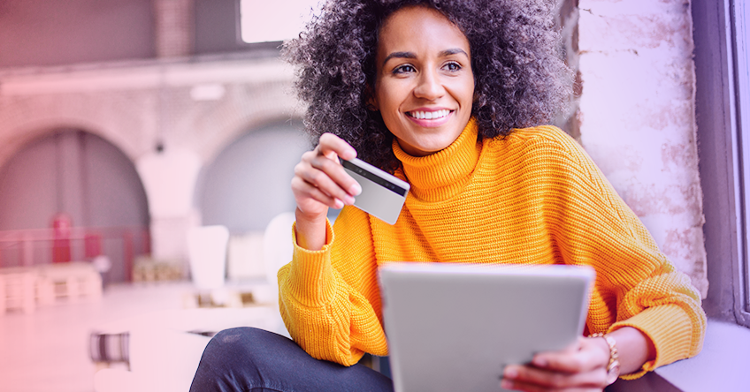 woman in yellow sweater with credit card and tablet
